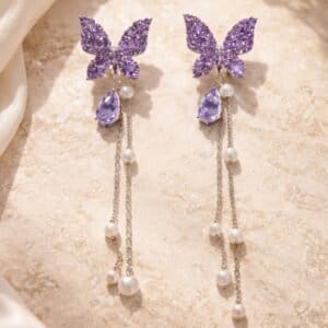 Elegant butterfly pearl chain earrings with purple glitter accents.