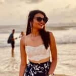 Woman in stylish summer outfit at the beach during sunset.