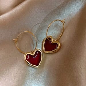 Gold hoop earrings with red heart-shaped charms, perfect for elegant and romantic jewelry styles.